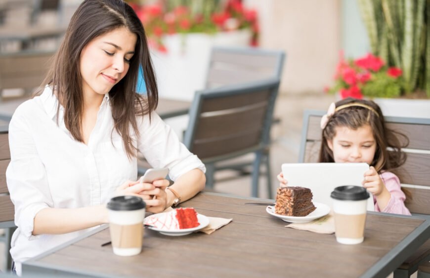 Mother and daughter at cafe using digital devices
